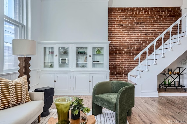 living area with stairway, brick wall, and wood finished floors