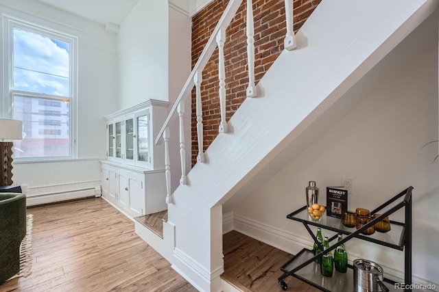 staircase with baseboard heating and wood finished floors