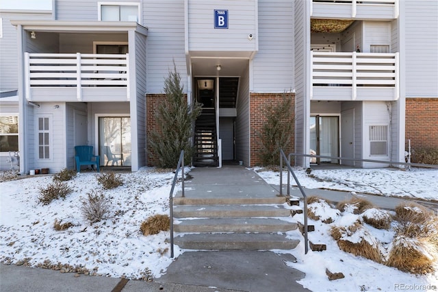 snow covered property entrance with brick siding