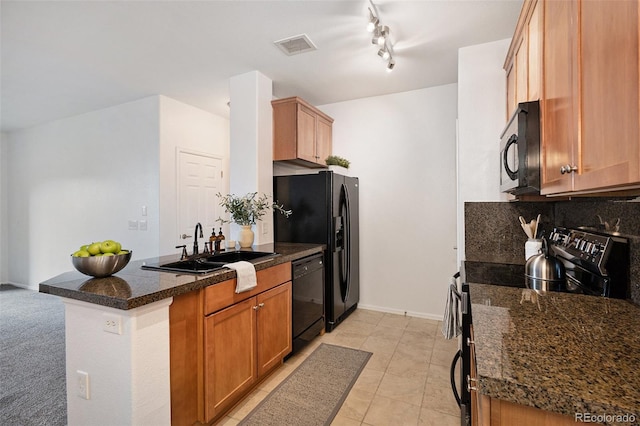 kitchen with sink, dark stone countertops, backsplash, black appliances, and kitchen peninsula