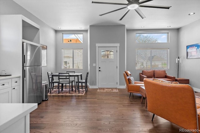 living room featuring ceiling fan, dark wood-type flooring, and a healthy amount of sunlight