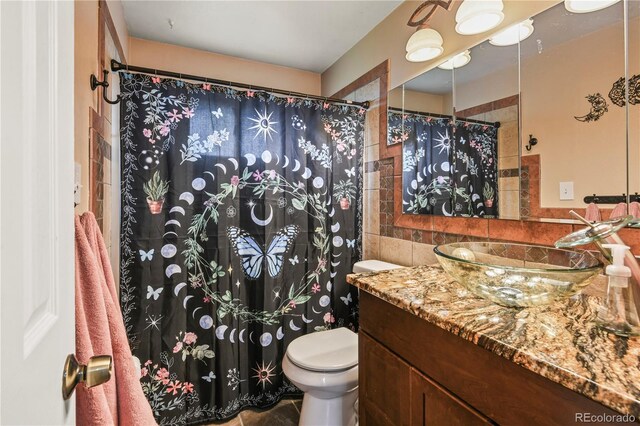 8410 Gray St, Arvada, CO 80003 - bathroom featuring toilet, vanity, tile walls, a shower with curtain, and backsplash