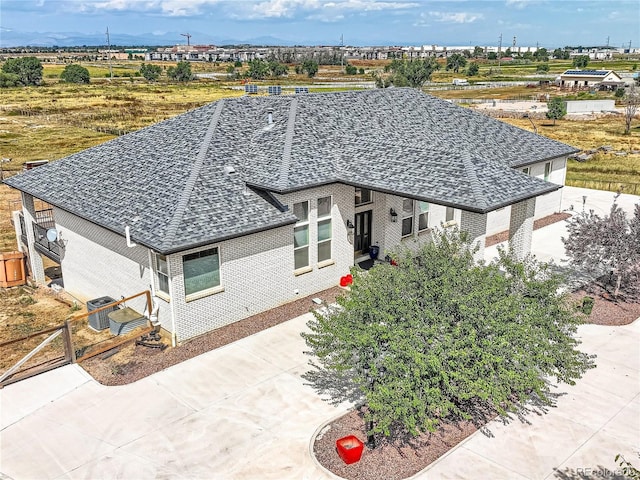 view of front of home featuring brick siding, fence, concrete driveway, and roof with shingles