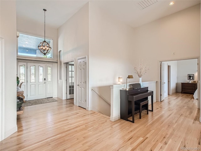 entryway featuring light hardwood / wood-style floors, a high ceiling, and a chandelier