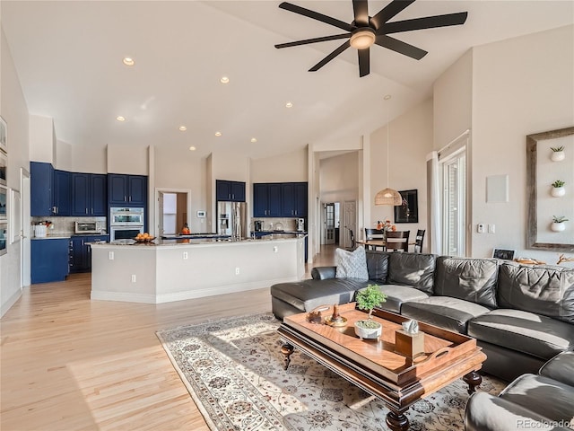 living room with light hardwood / wood-style flooring, ceiling fan, and high vaulted ceiling