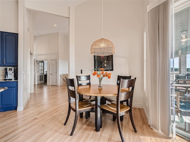 dining area featuring a towering ceiling and light hardwood / wood-style flooring