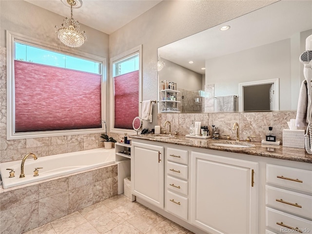 bathroom featuring backsplash, tiled bath, an inviting chandelier, dual bowl vanity, and tile patterned flooring