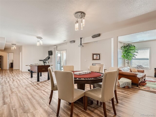 dining space featuring light hardwood / wood-style flooring and a textured ceiling