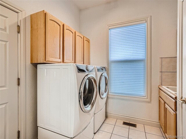 laundry area with independent washer and dryer, light tile patterned floors, and cabinets