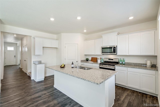 kitchen with white cabinets, sink, stainless steel appliances, and an island with sink