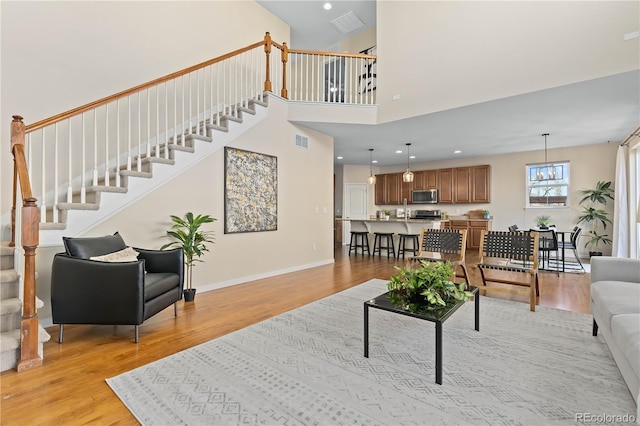 living room featuring a chandelier, a high ceiling, and light wood-type flooring