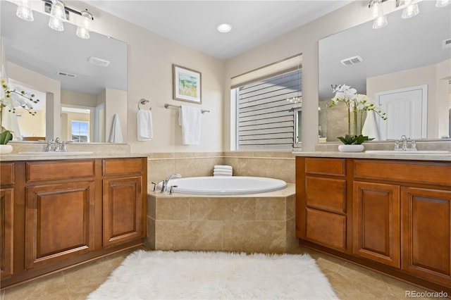 bathroom with a relaxing tiled tub, tile patterned floors, vanity, and plenty of natural light