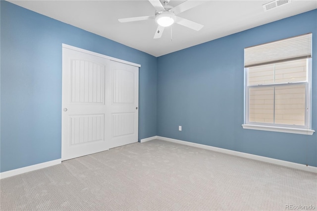 unfurnished bedroom featuring light carpet, ceiling fan, and a closet
