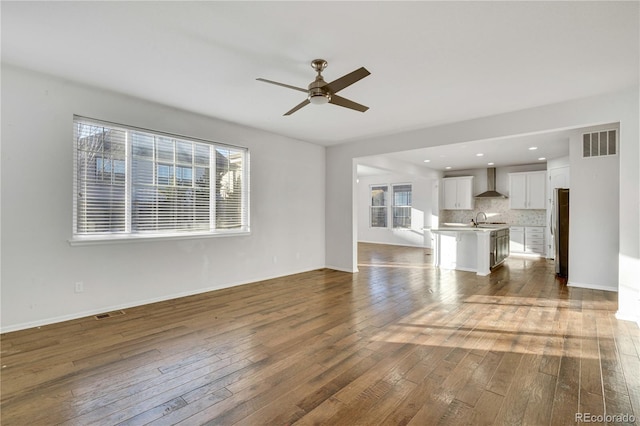 unfurnished living room with dark hardwood / wood-style floors, ceiling fan, plenty of natural light, and sink