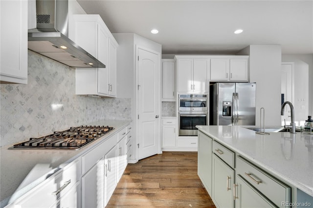 kitchen featuring dark hardwood / wood-style floors, white cabinetry, wall chimney range hood, and stainless steel appliances