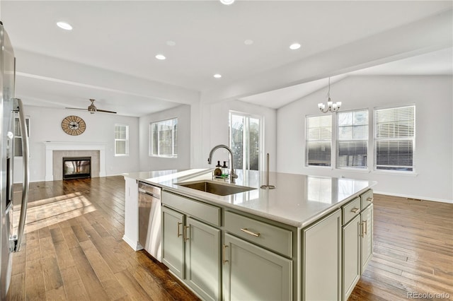 kitchen featuring a tile fireplace, dishwasher, sink, an island with sink, and hardwood / wood-style flooring