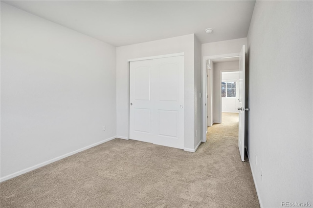 unfurnished bedroom featuring light colored carpet and a closet