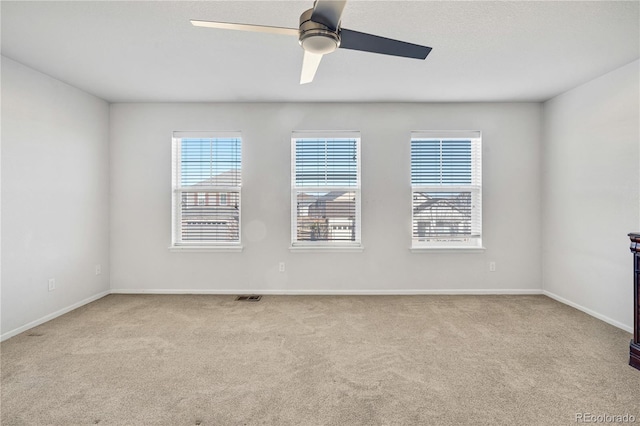 empty room with light carpet, a wealth of natural light, and ceiling fan