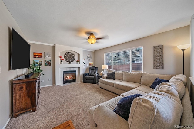 living room featuring ceiling fan, carpet, a fireplace, and baseboards