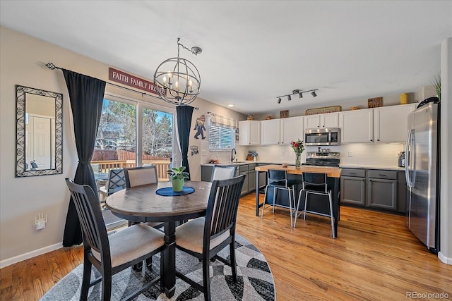 dining area with a chandelier, light wood-type flooring, and baseboards