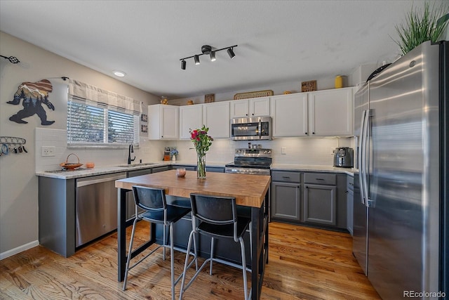 kitchen featuring light wood-style flooring, wood counters, appliances with stainless steel finishes, a kitchen breakfast bar, and a sink