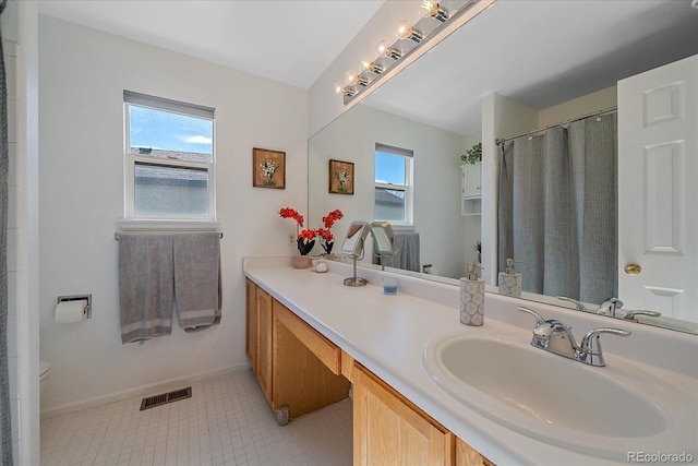 full bath with visible vents, plenty of natural light, vanity, and baseboards