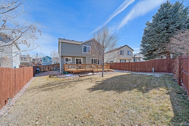 rear view of house with a fenced backyard, a yard, and a wooden deck