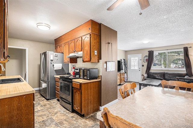 547 S 3rd Ave, Brighton, CO 80601 - kitchen with under cabinet range hood, a sink, stainless steel appliances, brown cabinetry, and a textured ceiling