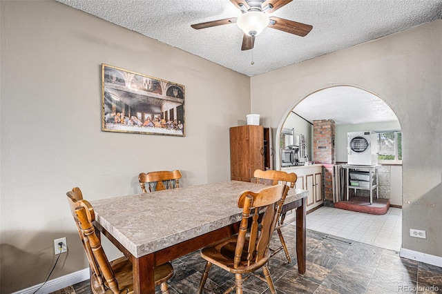 547 S 3rd Ave, Brighton, CO 80601 - dining room with arched walkways, a textured ceiling, a ceiling fan, and baseboards