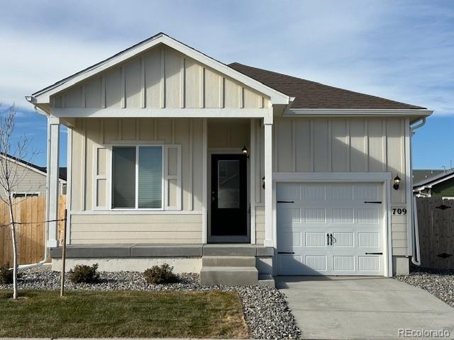 709 Twining Ave, Brighton, CO 80601 - view of front of property with board and batten siding, fence, a garage, concrete driveway, and roof with shingles