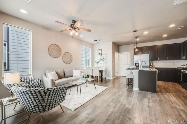 living room with sink, ceiling fan, and light hardwood / wood-style floors