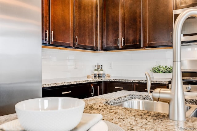 kitchen featuring decorative backsplash, sink, and light stone counters