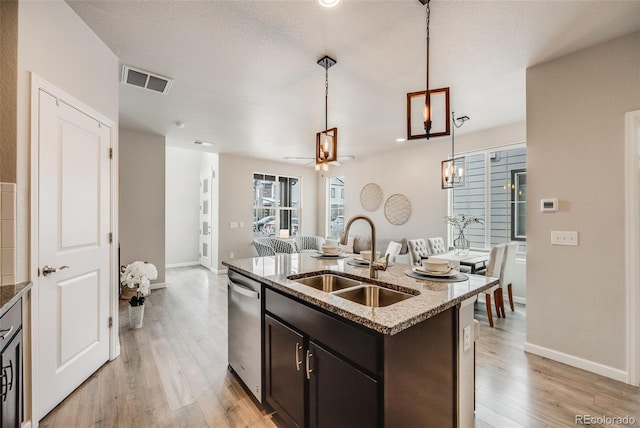 kitchen with light wood-type flooring, a center island with sink, hanging light fixtures, sink, and dishwasher