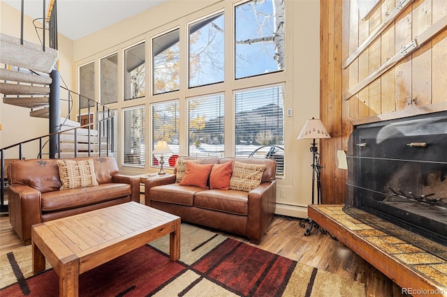 living room with a towering ceiling, a tile fireplace, a healthy amount of sunlight, and light hardwood / wood-style flooring