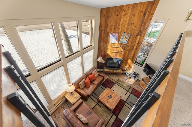 living room featuring wooden walls, a wealth of natural light, vaulted ceiling, and a large fireplace