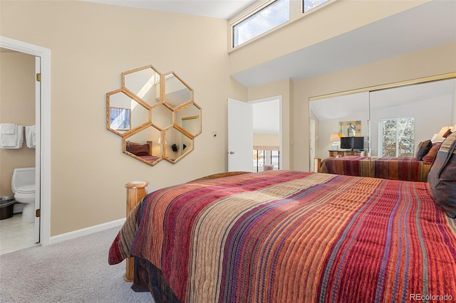 bedroom with carpet flooring, lofted ceiling, multiple windows, and connected bathroom