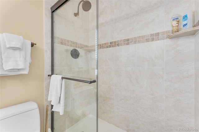 bathroom featuring a shower with shower door and toilet