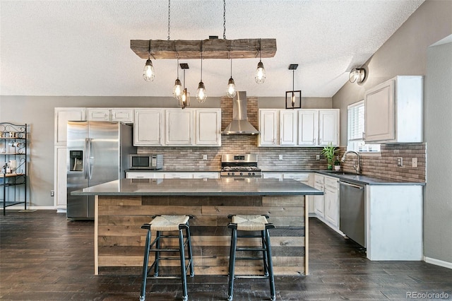 kitchen with a sink, a center island, stainless steel appliances, wall chimney exhaust hood, and vaulted ceiling