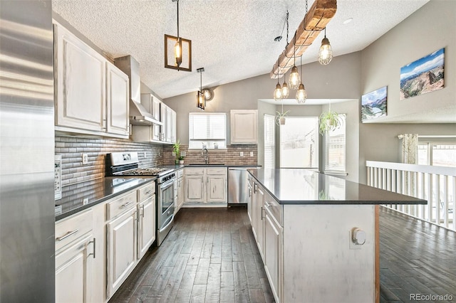 kitchen with a sink, dark countertops, vaulted ceiling, and stainless steel appliances