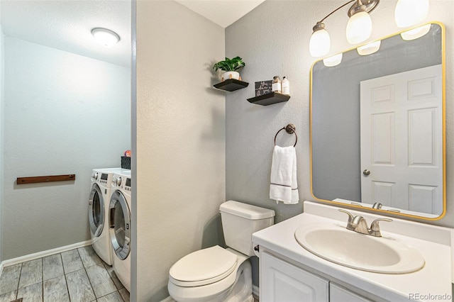 half bath with washing machine and clothes dryer, baseboards, toilet, a textured wall, and vanity