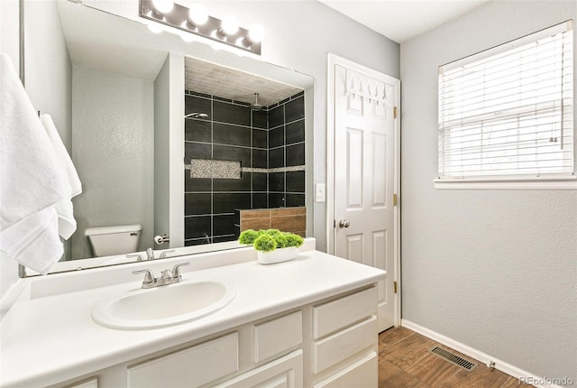 bathroom featuring visible vents, toilet, wood finished floors, baseboards, and vanity