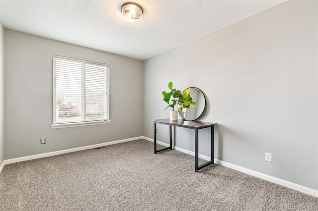 carpeted spare room featuring baseboards and a textured ceiling