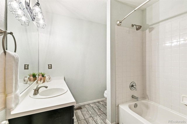 bathroom featuring baseboards, toilet, bathing tub / shower combination, wood finished floors, and vanity