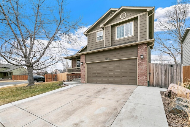 traditional home with brick siding, an attached garage, driveway, and fence