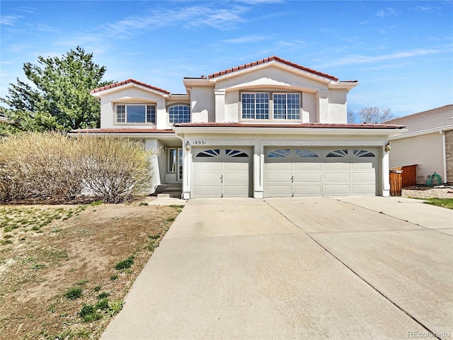 18951 E 43rd Ave, Denver, CO 80249 - view of front facade with stucco siding, an attached garage, a tiled roof, and concrete driveway