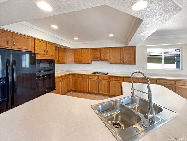 18951 E 43rd Ave, Denver, CO 80249 - kitchen featuring brown cabinets, light wood finished floors, light countertops, a sink, and black appliances