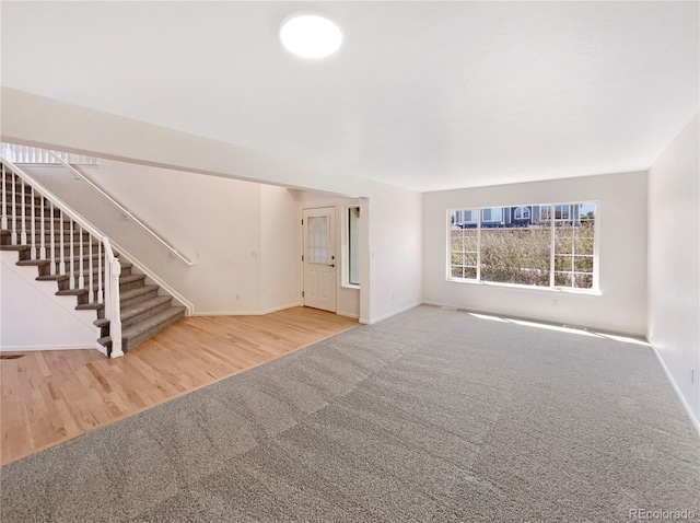 18951 E 43rd Ave, Denver, CO 80249 - unfurnished living room featuring baseboards, wood finished floors, stairs, and carpet
