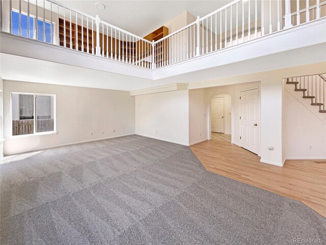 18951 E 43rd Ave, Denver, CO 80249 - unfurnished living room featuring carpet flooring, arched walkways, baseboards, a towering ceiling, and stairs