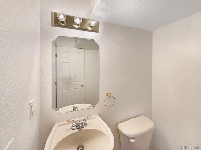 18951 E 43rd Ave, Denver, CO 80249 - half bath featuring a textured wall, a sink, and toilet