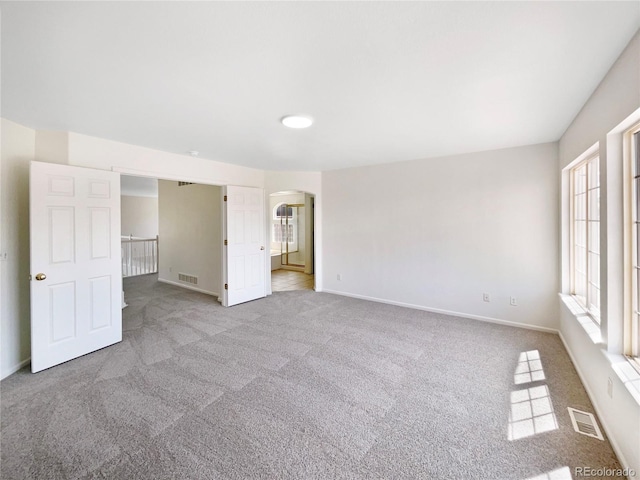 18951 E 43rd Ave, Denver, CO 80249 - unfurnished bedroom featuring arched walkways, carpet, visible vents, and baseboards